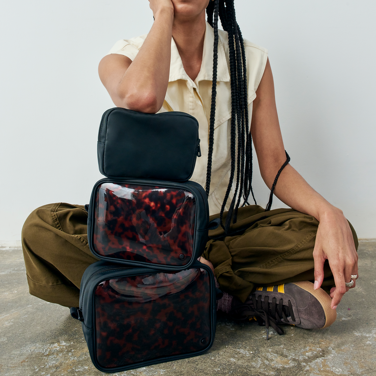 woman sitting with STATE Bags Travel Pouch Set of Three Tortoise