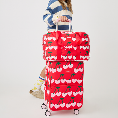 girl pushing STATE Bags Logan Carry-On Suitcase Cherry with Rockaway Cherry