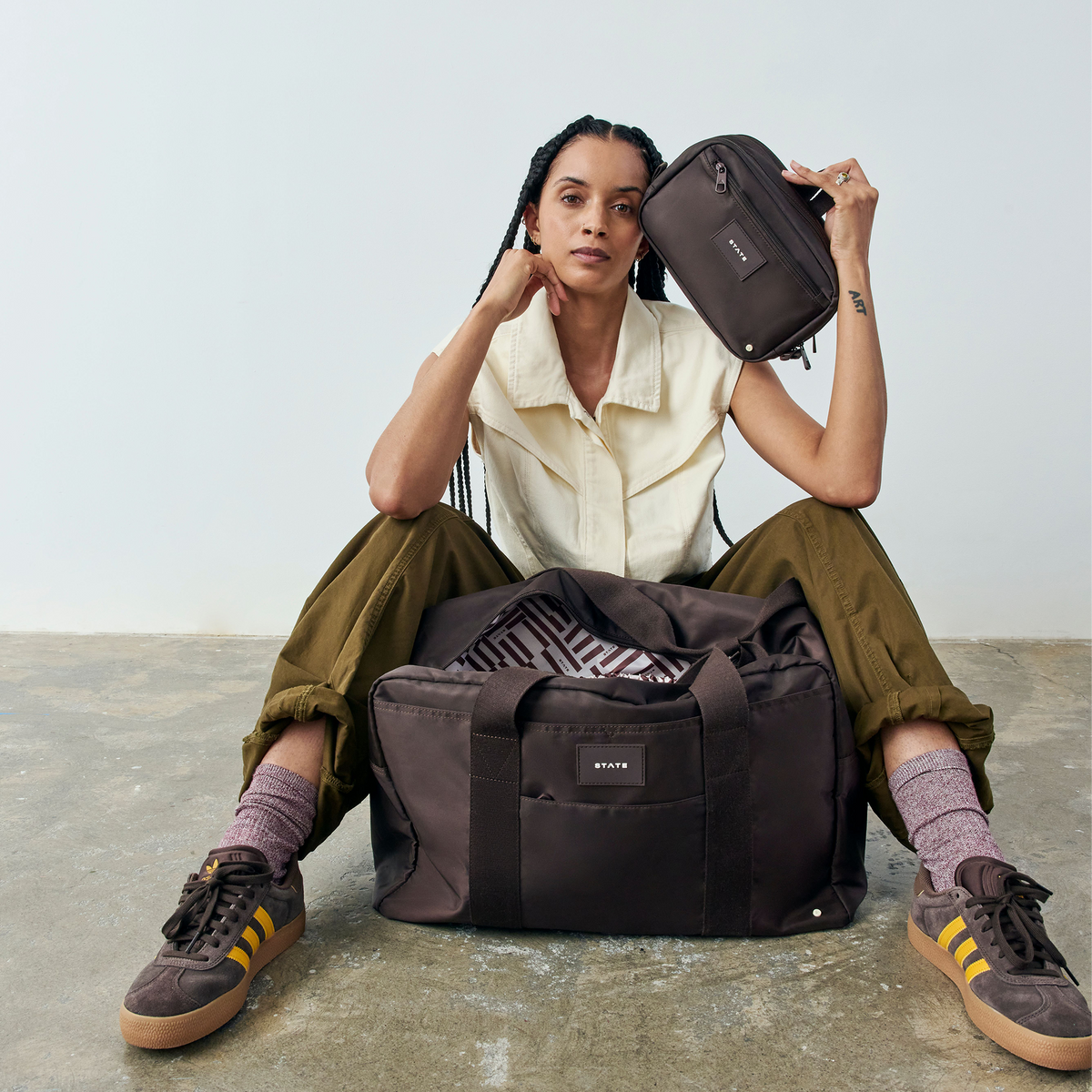 woman sitting with state bags wellington weekender and hart toiletry kit brown