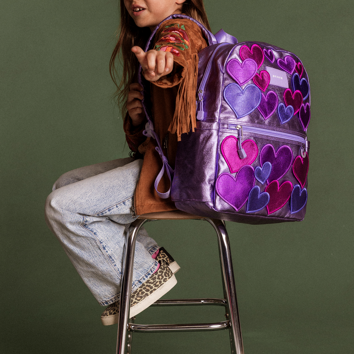 girl sitting on stool wearing kane backpack 3d hearts