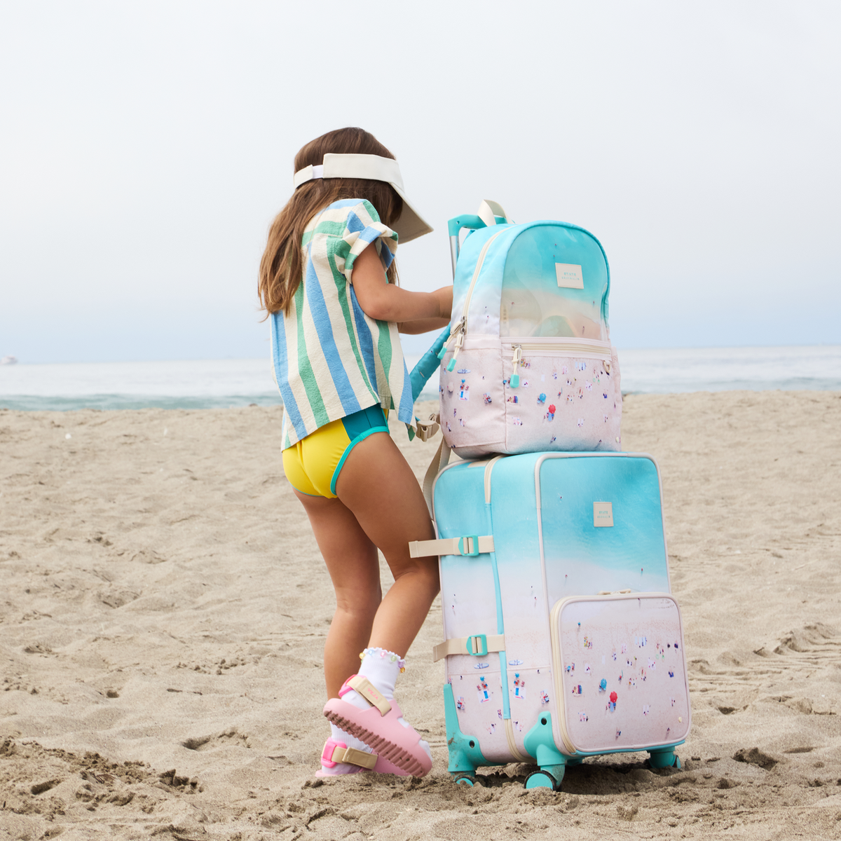 girl standing with STATE x Gray Malin Logan Carry-On Suitcase