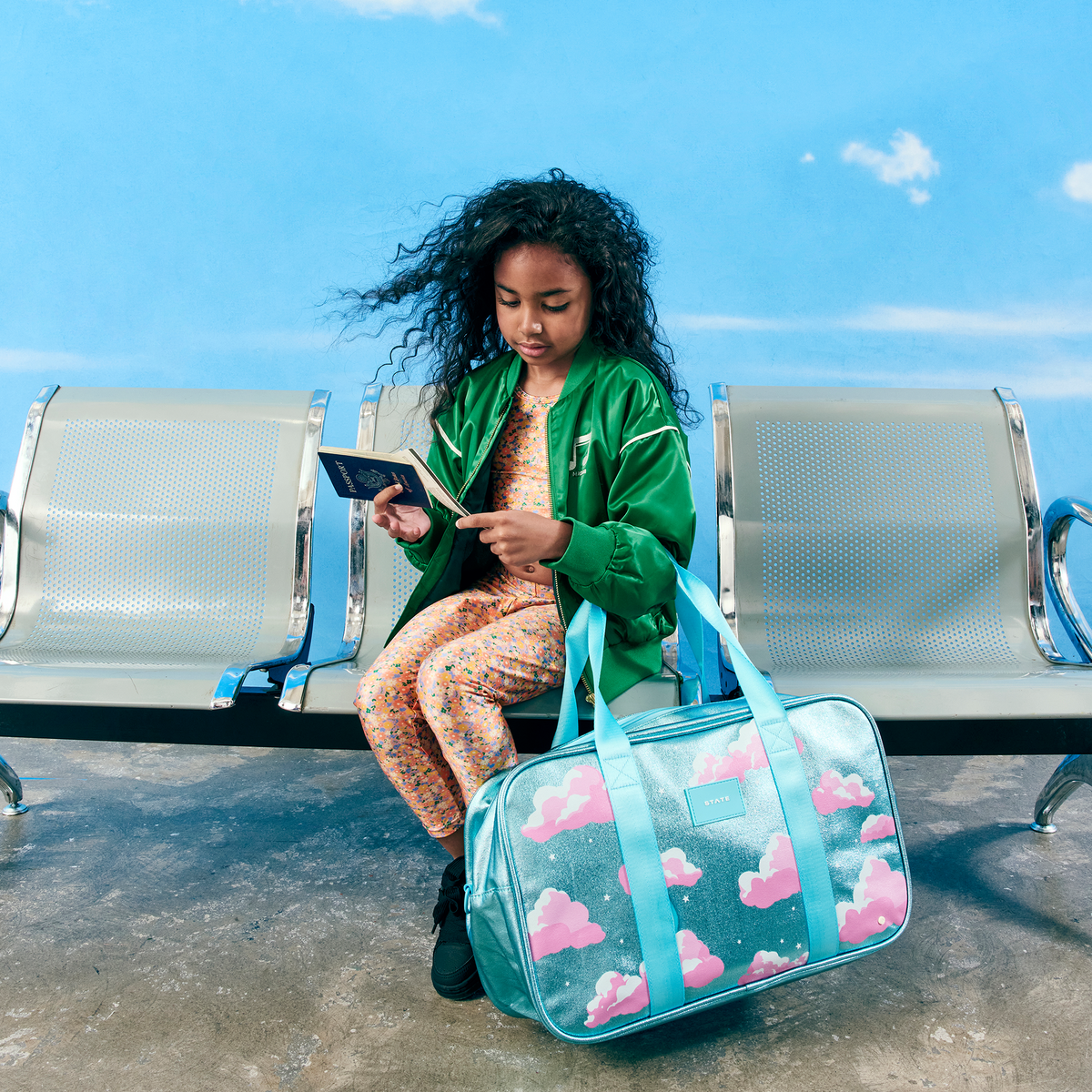 girl sitting holding STATE Bags Rockaway Duffle Clouds