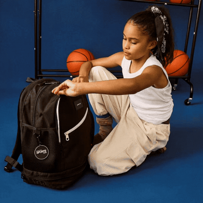 girl putting ball into STATE Bags Ozzie Ball Bag