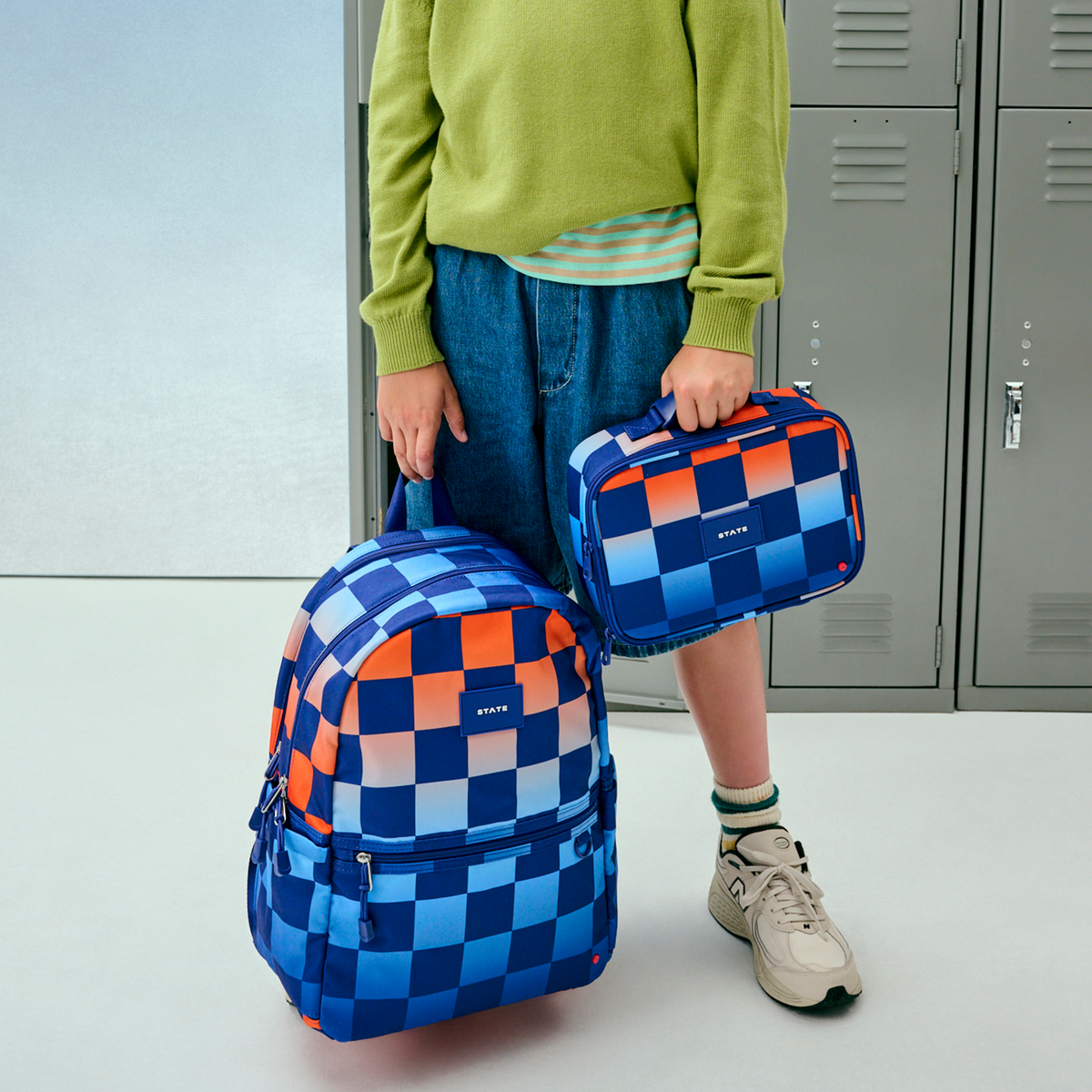 boy standing holding kane double pocket backpack blue checkerboard