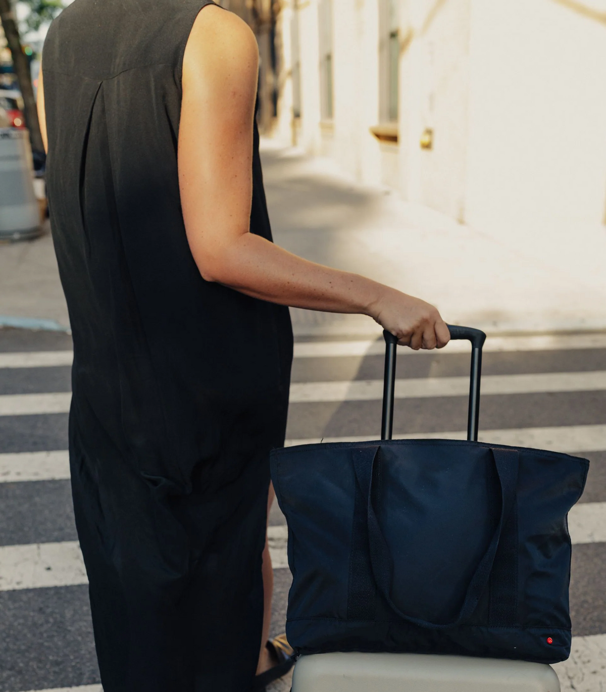 Woman walking with black tote on suitcase